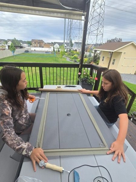 Sisters carefully rescreening a frame
