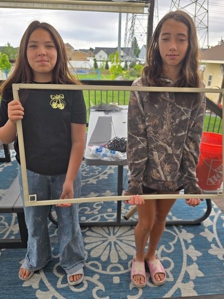 Millie and Evie holding a freshly repaired window screen